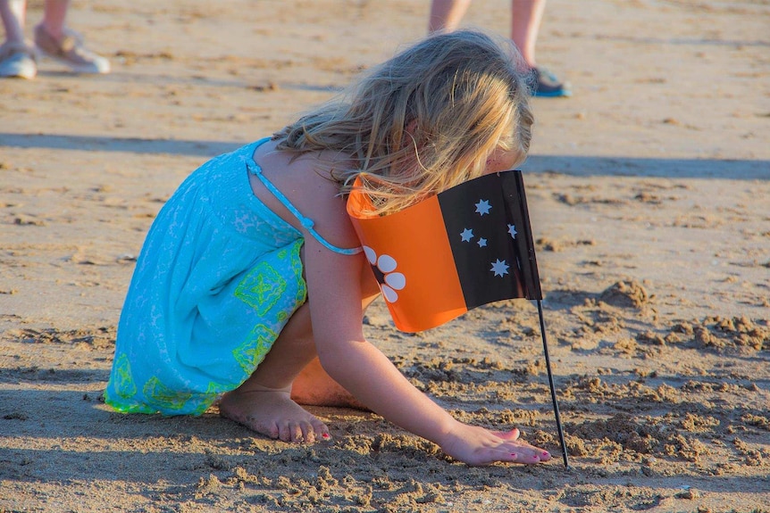 A little girl with an NT flag on the beach
