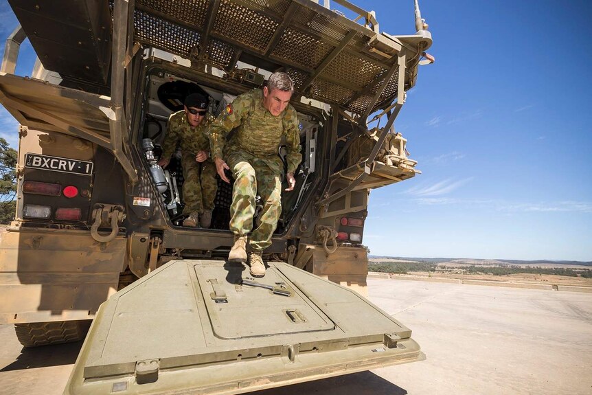 Chief of Army Lieutenant General Angus Campbell and another soldier climb out of the back of the Boxer CRV