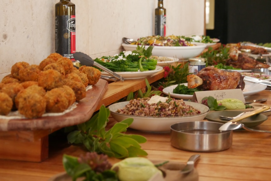 a spread of salad, meat and arancini balls.