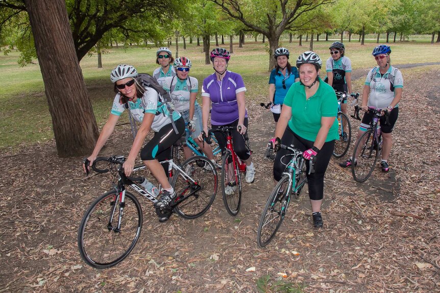 Women in cycling gear on bikes sitting on bikes in a park