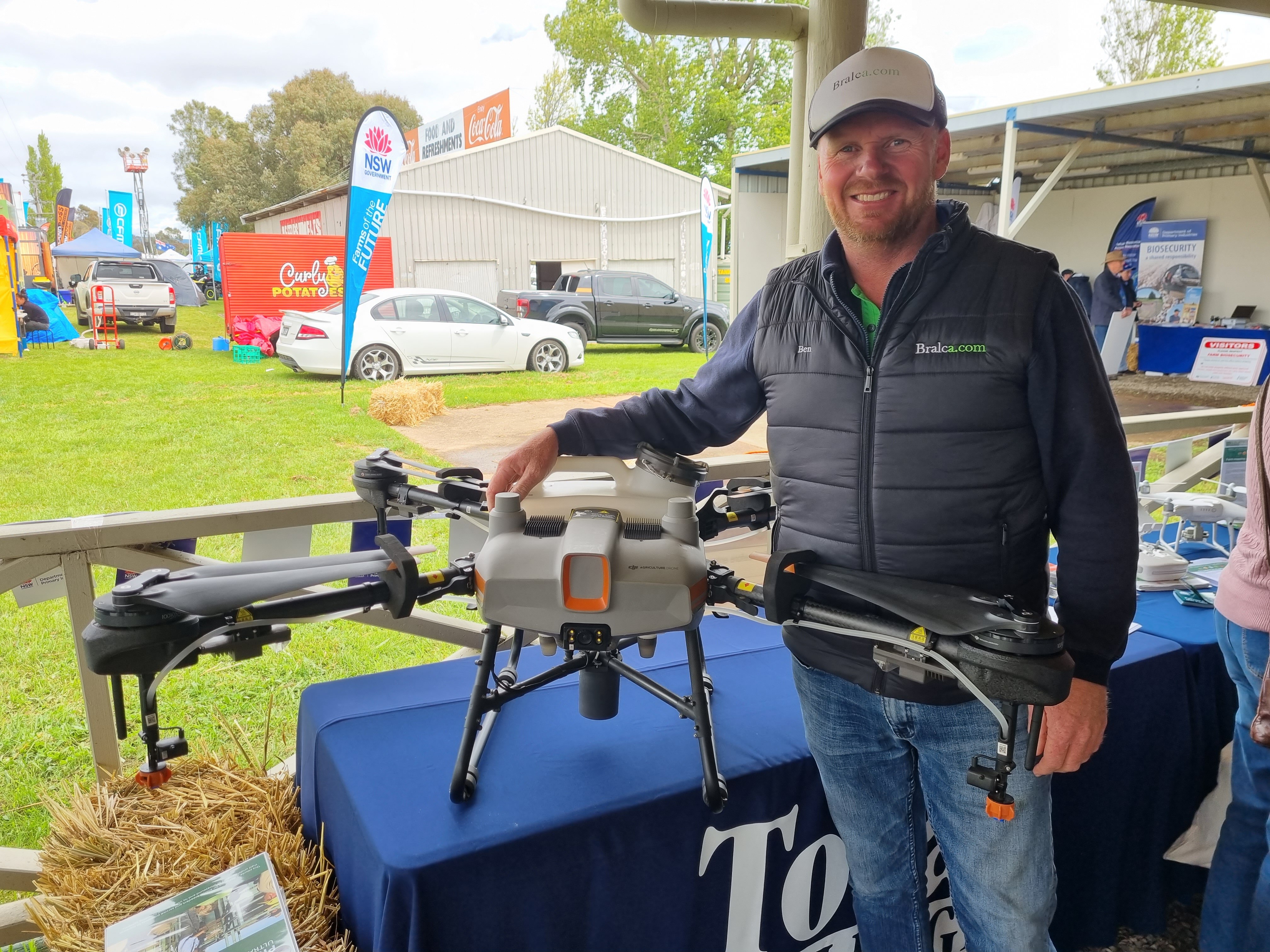 A bearded man standing next to an agriculture drone