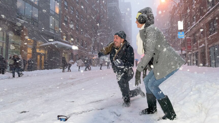 Two people play snowball game on New York street.