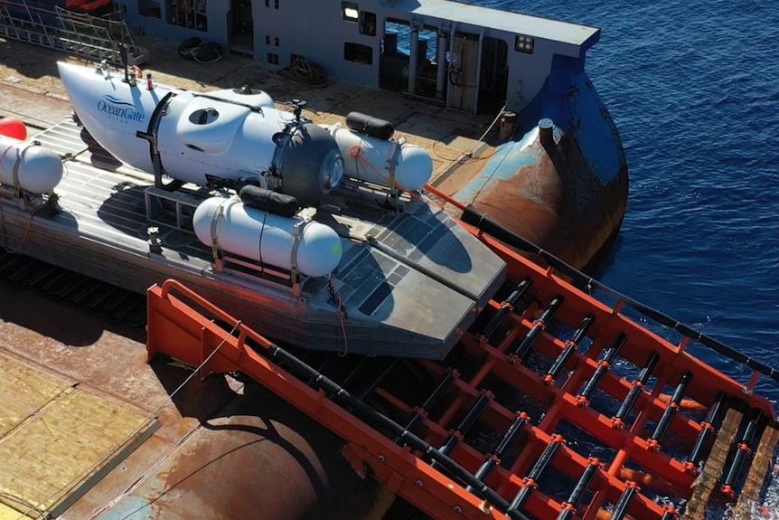 A submersible vessel sits on a contraption on the deck of a ship, about to launch off a ramp