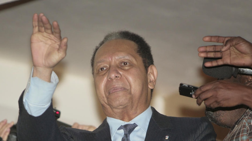 Former Haitian dictator Jean-Claude "Baby-Doc" Duvalier waves from a hotel in Petionville, Haiti