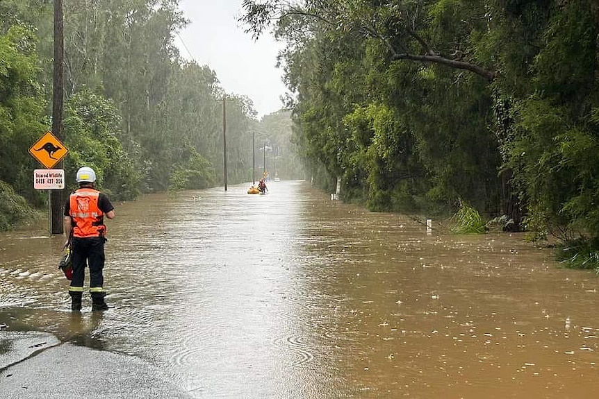 two sate emergency service volunteers on a flooded road with one on a rubber boat