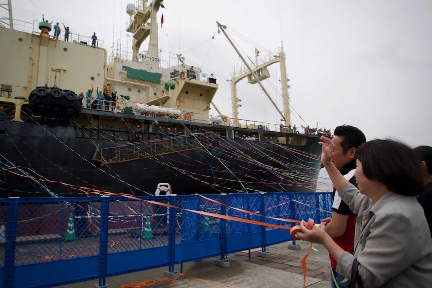 People throw streams at a big ship