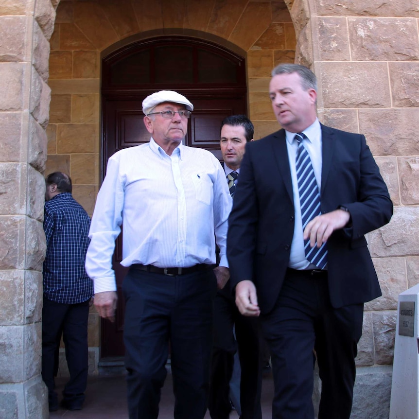 Don Spiers walks out of court with a police officer accompanying him.