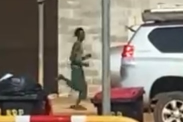 A blurry image of a tall thin man running down a street