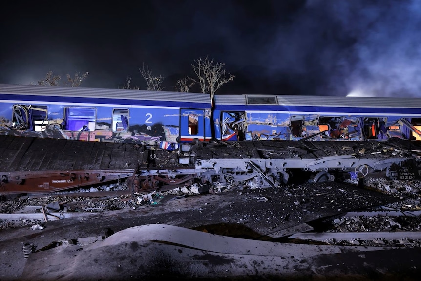 Eerie view of graffiti on blue crashed train site at night. 