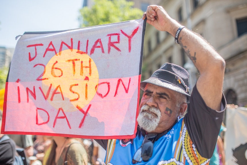 一位原住民男子在墨尔本的侵略日（Invasion Day）大型集会上高举标语。