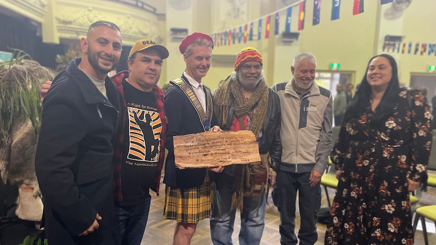 Five men and a woman holding an inscribed piece of bark