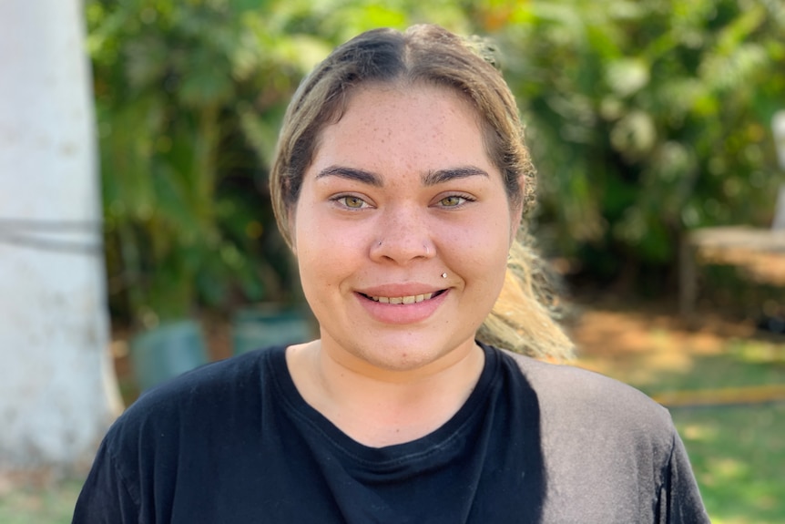 A girl in a  black tshirt smiles at the camera