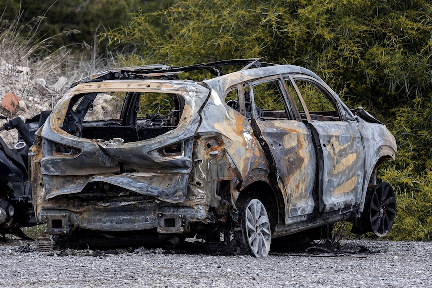A burnt out hatchback car parked