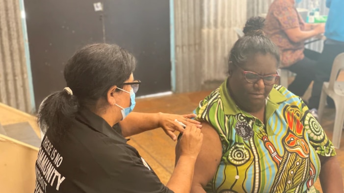 An Indigenous woman receives a COVID jab.