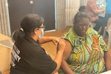 An Indigenous woman receives a COVID jab.