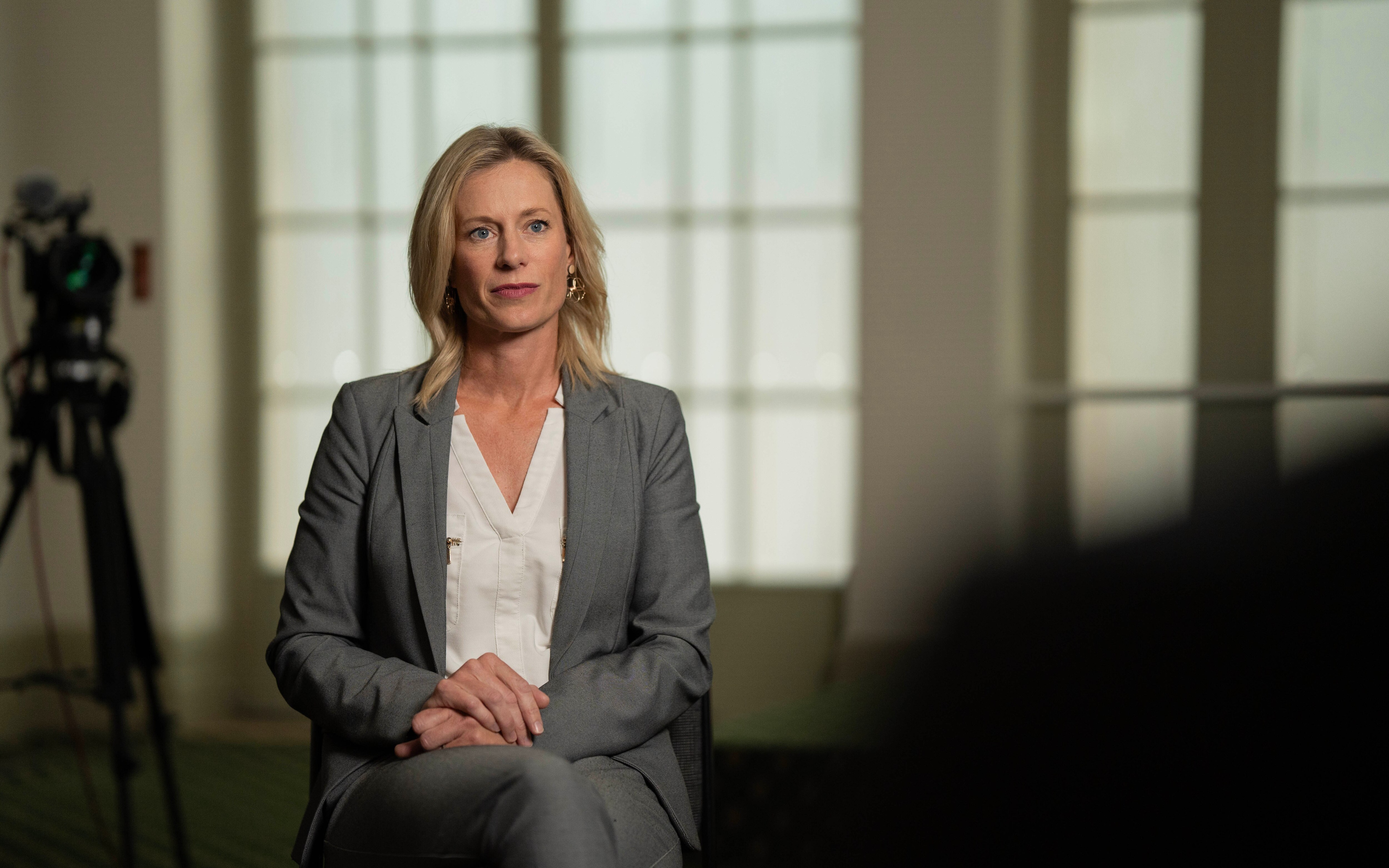 A female politician during an interview with a journalist surrounded by three cameras, microphones and a light.