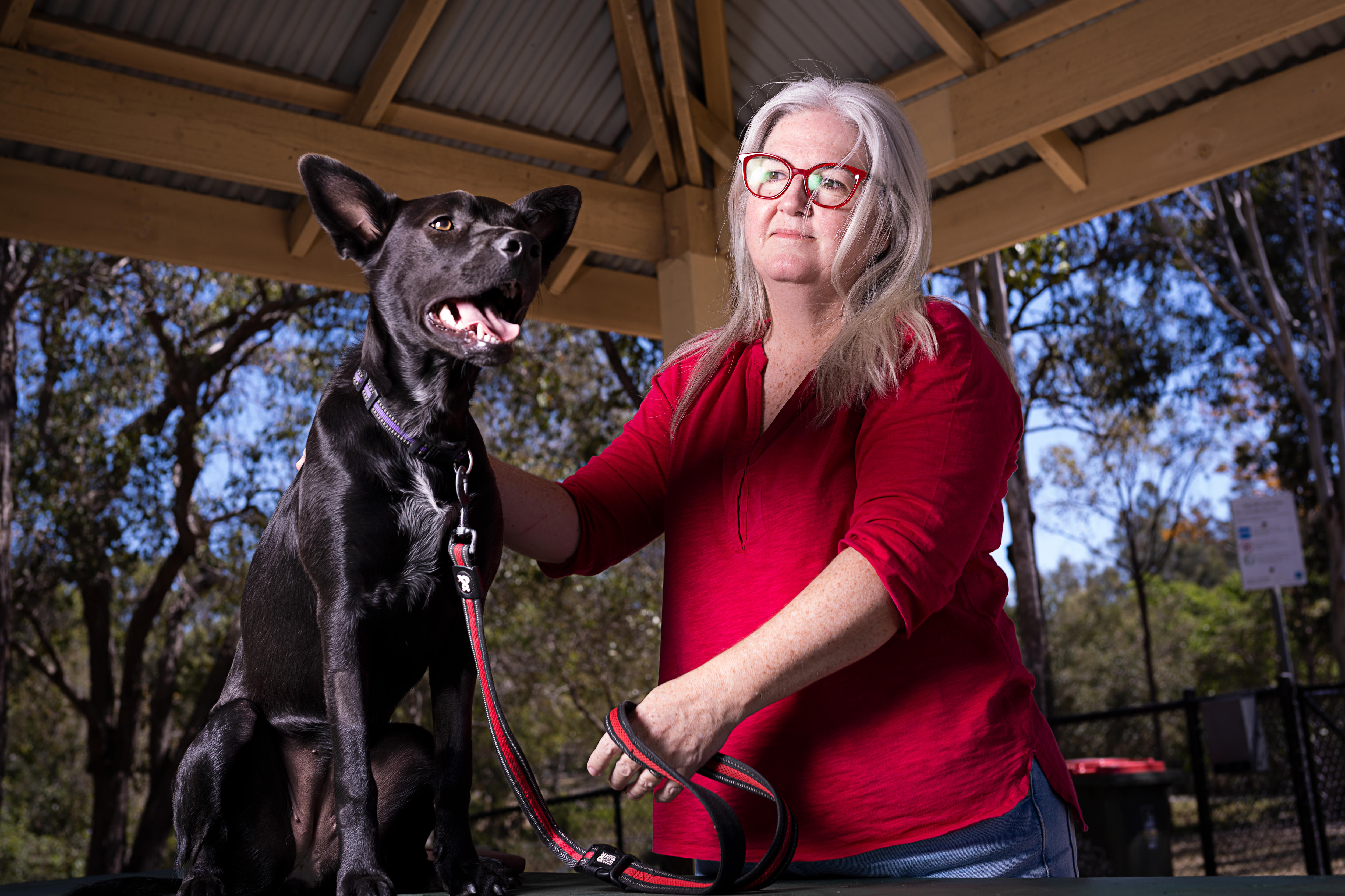An Australian Kelpie and a woman wearing a red top.