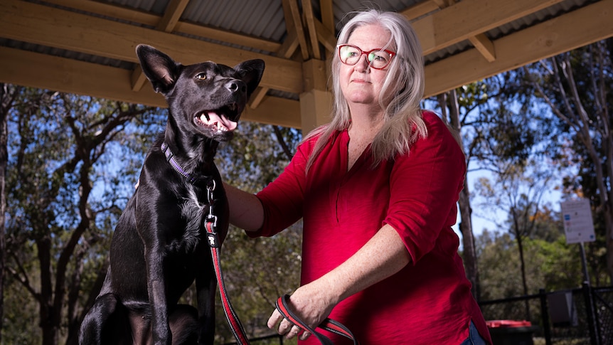 An Australian Kelpie and a woman wearing a red top.