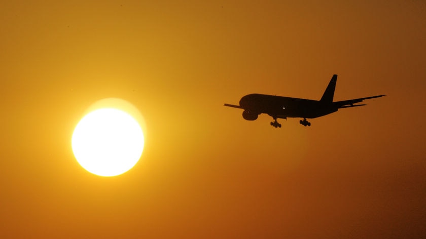 A plane flying into a sunset