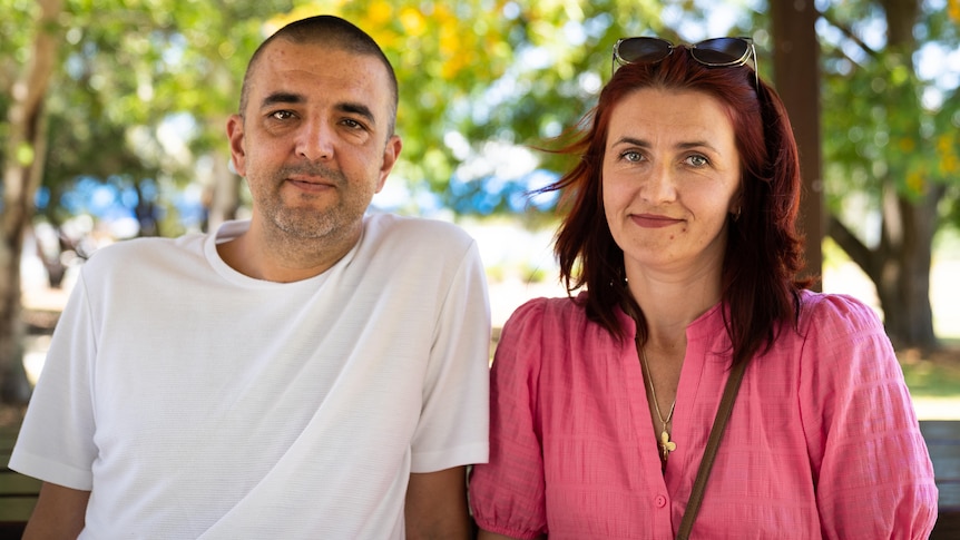 couple sitting on park bench smiling at camera