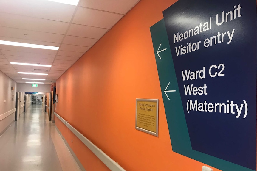 Maternity ward sign on an orange wall points down corridor inside Wollongong Hospital