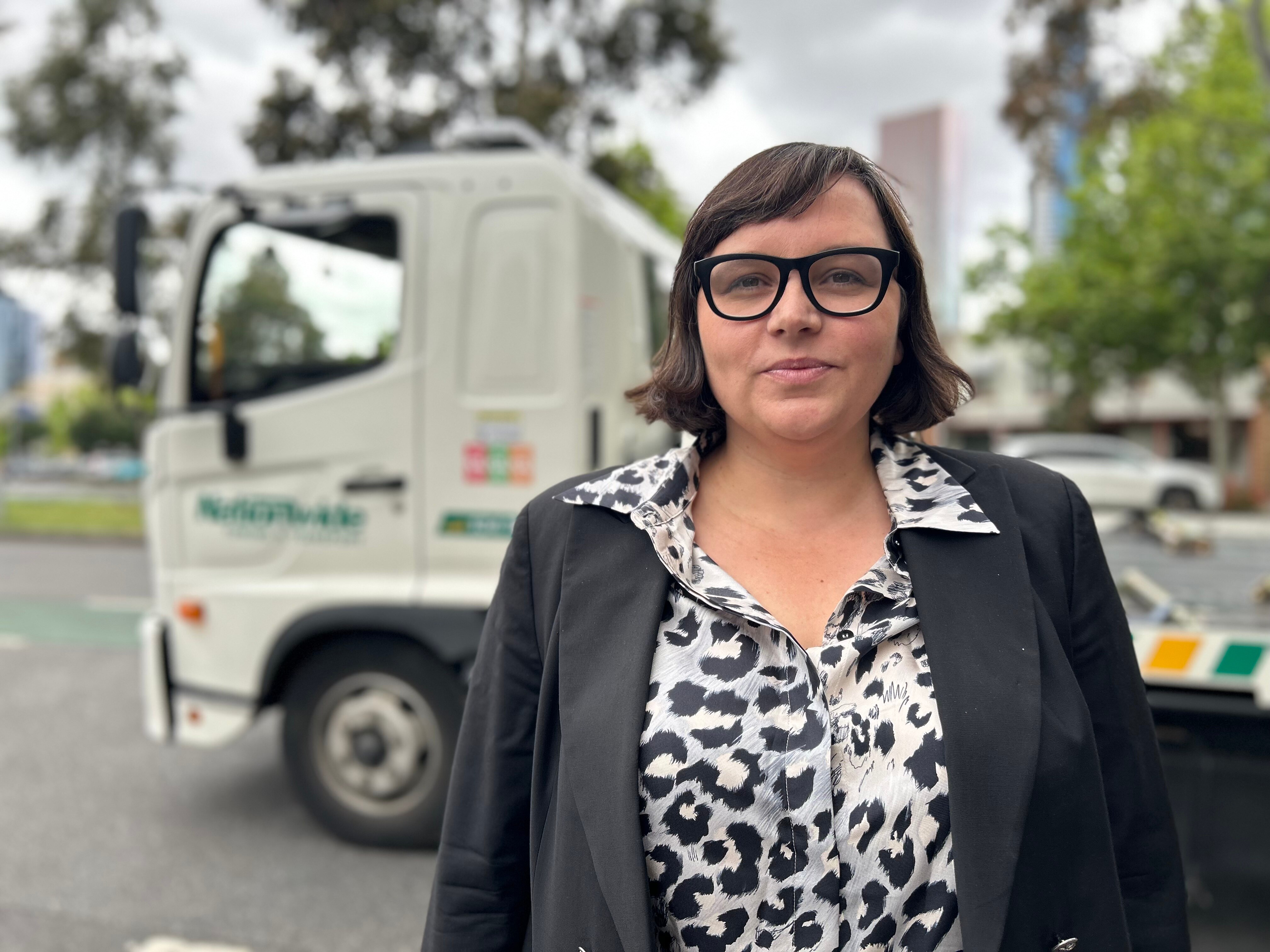 Erin Turner stands in front of a tow truck. 