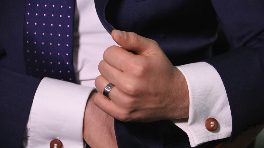 Tim Wilson adjusting his cufflinks with his wedding ring on full display.