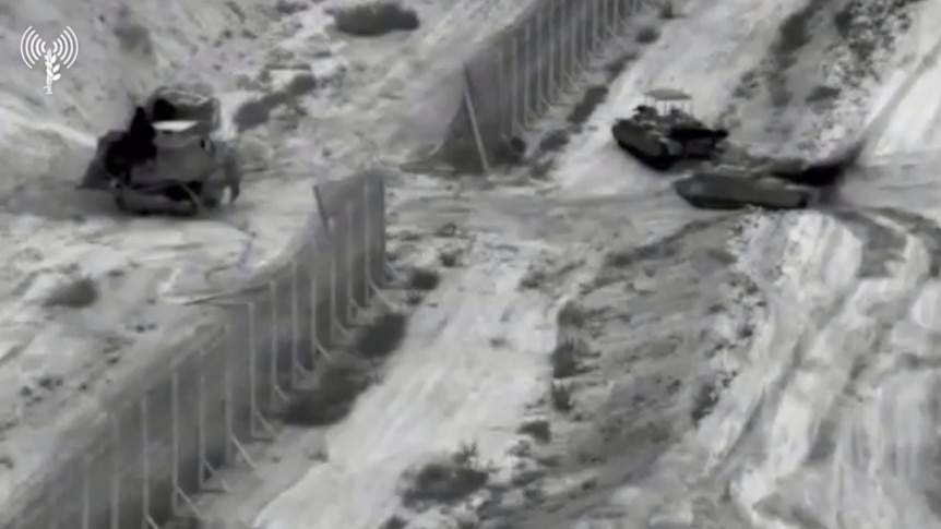 Black and white video released by the IDF seeming to show Israeli military entering a gap in a border fence