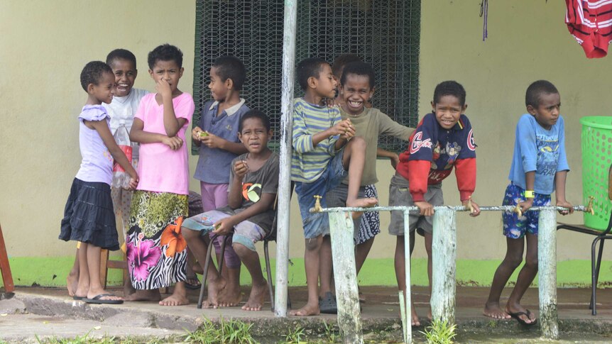 Children gather outside a school building after Tropical Cyclone Winston flattened homes in Fiji.