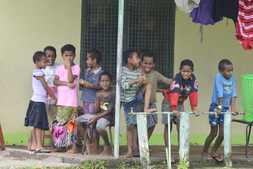 Children gather outside a school building after Tropical Cyclone Winston flattened homes in Fiji.