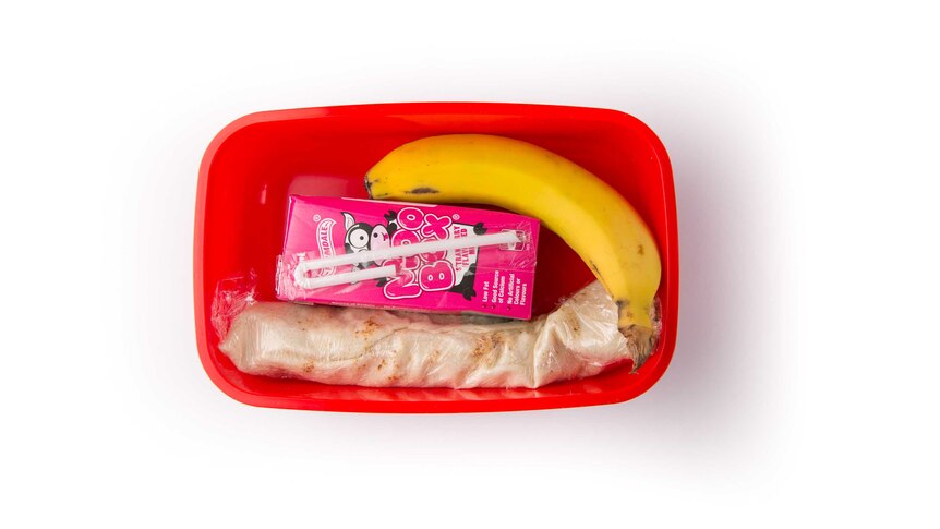 Cheese in pita bread, a banana and a strawberry flavoured milk box in a red lunch box.