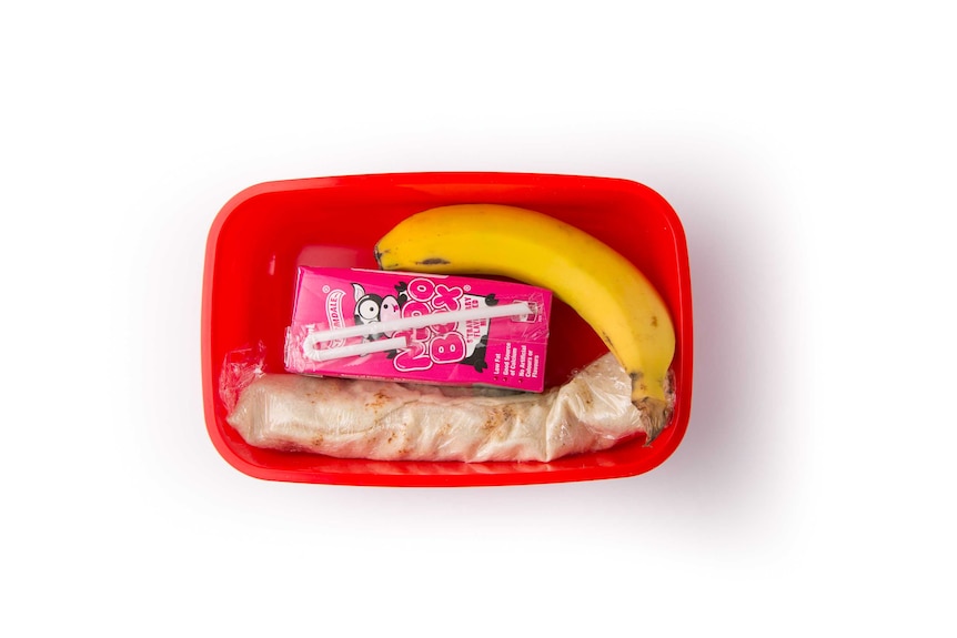 Cheese in pita bread, a banana and a strawberry flavoured milk box in a red lunch box.