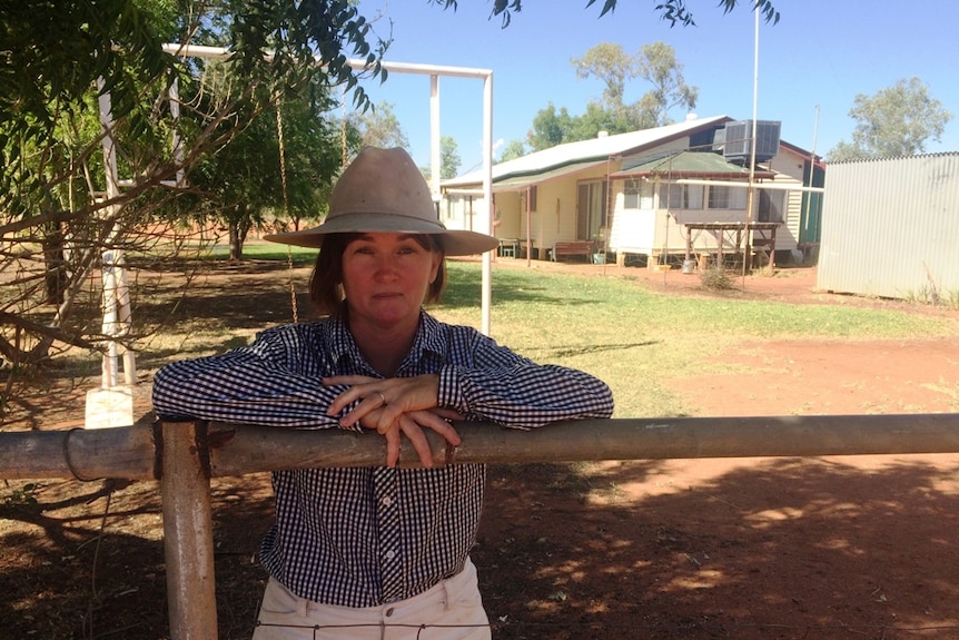 Grazier Kalinda Cluff leans on a fence, her homestead in the background.