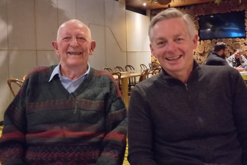 Brisbane father and son, Peter and Chris Healy, in a restaurant smiling.