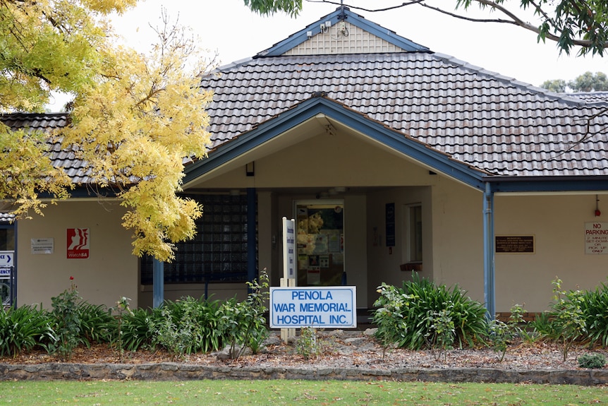 The front of a building with the tiled roof and garden out the front, a sign reads "Penola War Memorial Hospital Inc"