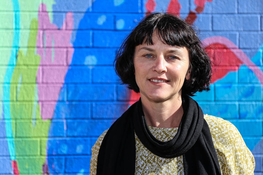 Elysium 2481 curator Rebecca Townsend stands in front of a mural in Byron Bay's Lateen Lane