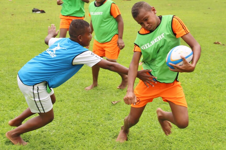 A boy tries to escape from a would-be tackler in a game of touch rugby.