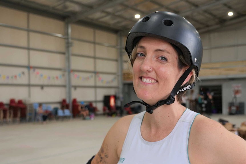 A woman stands inside a huge shed wearing a helmet.