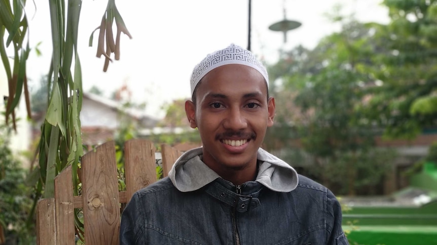 Seorang pria muslim memakai peci putih difoto menghadap ke kamera