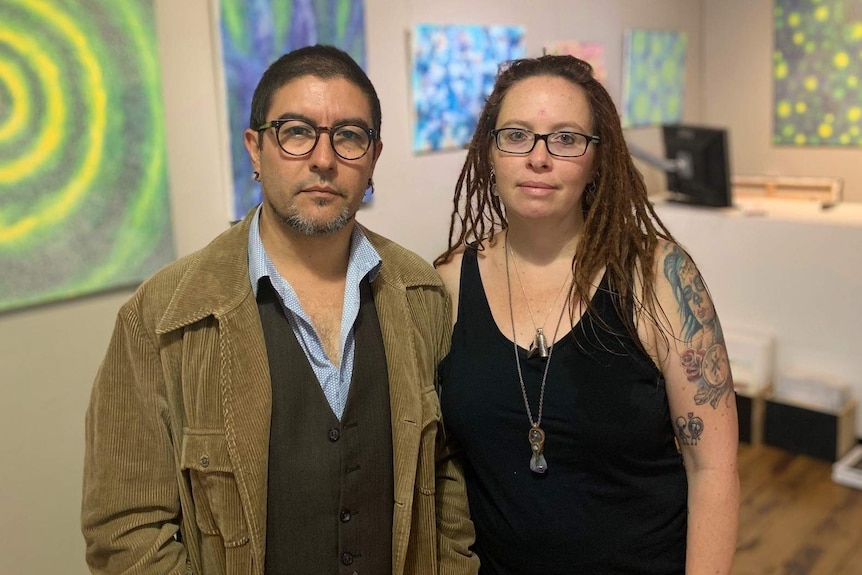 Victor and Sharon Peralta stand in a room with art on the walls.