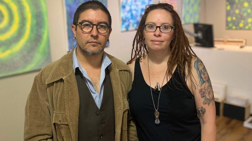 Victor and Sharon Peralta stand in a room with art on the walls.