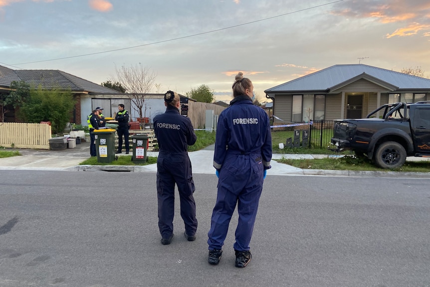 Officers in forensics uniforms outside a house.