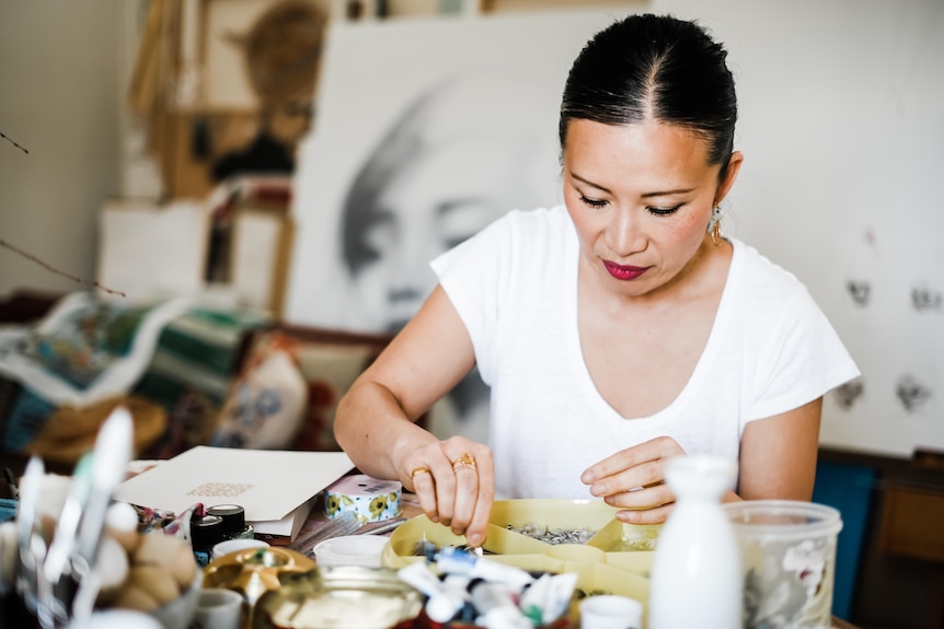 A woman sorts through bird feathers.