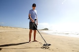 A man with a metal detector at Nobbys beach