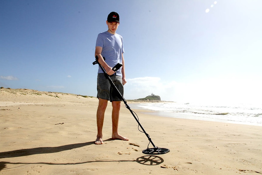 A man with a metal detector at Nobbys beach