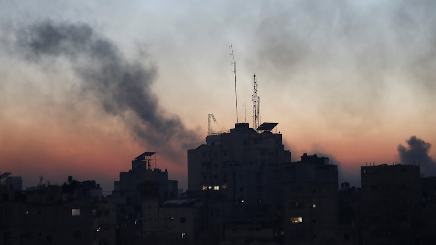 The silhouette of buildings are pictured with smoke rising above it. 