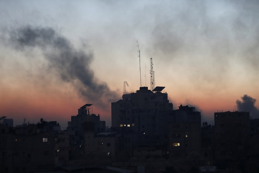 The silhouette of buildings are pictured with smoke rising above it. 