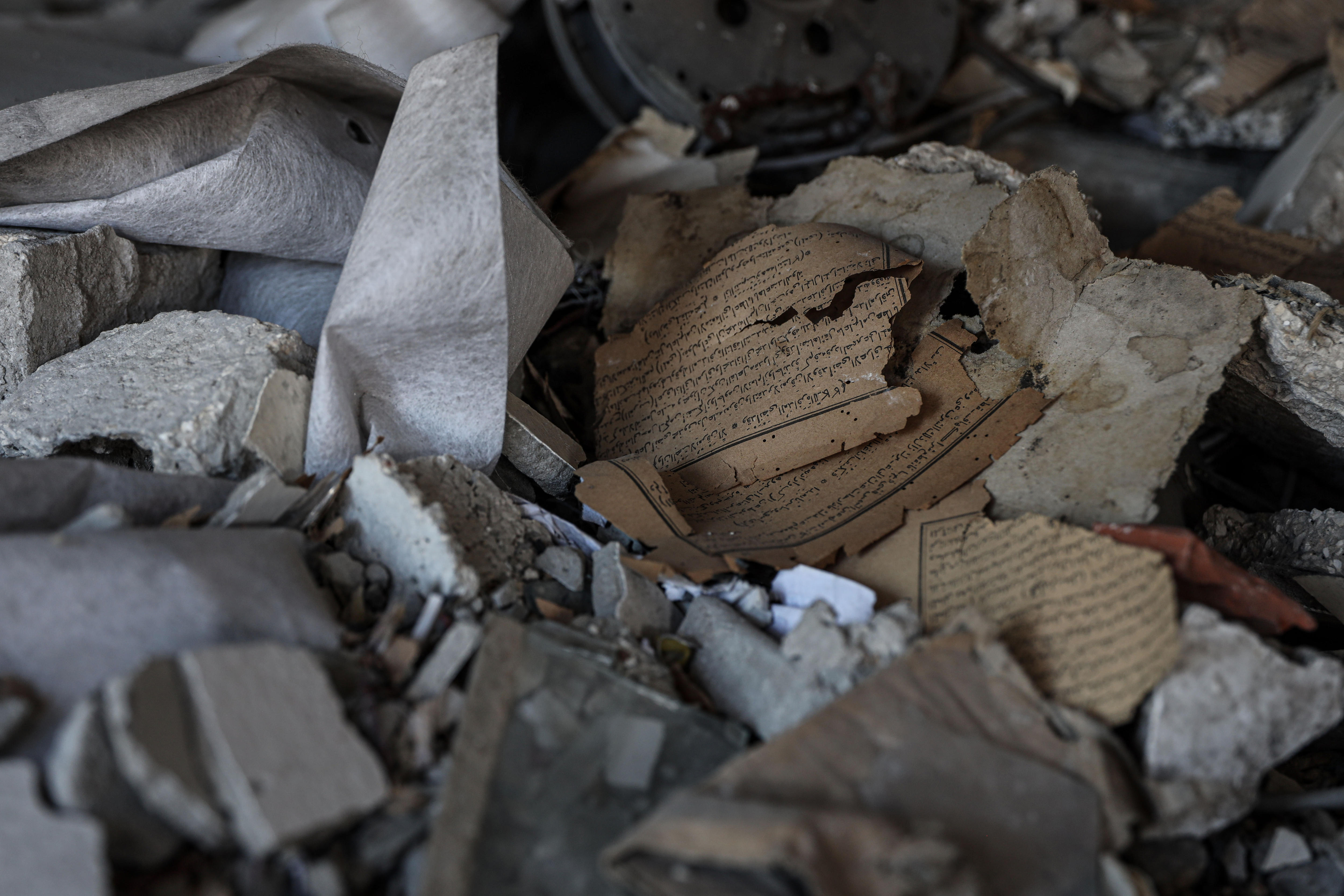 A damaged manuscript with ripped pages sits in a pile of rubble.