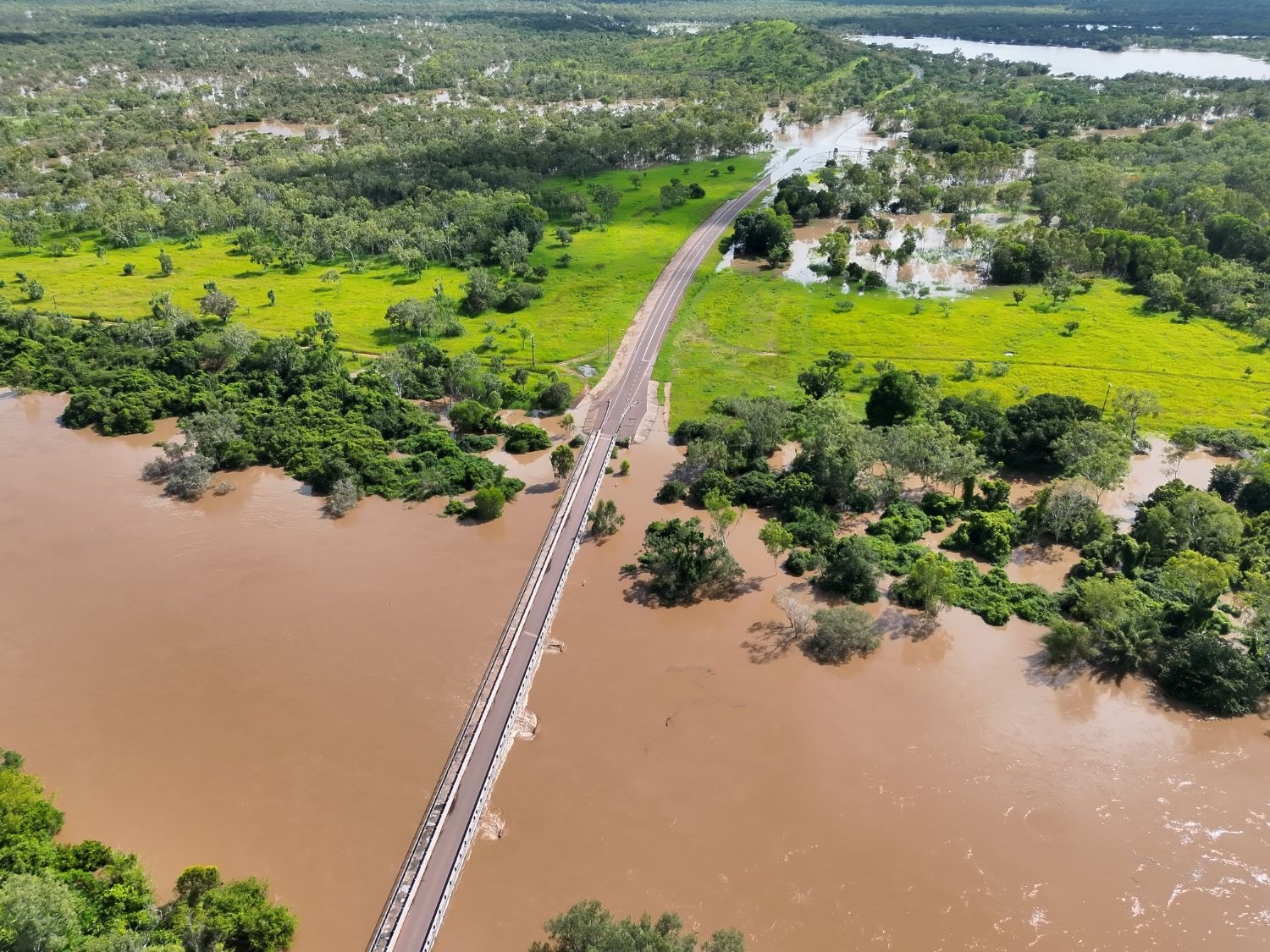 Una carretera estrecha que atraviesa una zona remota, verde y exuberante con profundas inundaciones a ambos lados.
