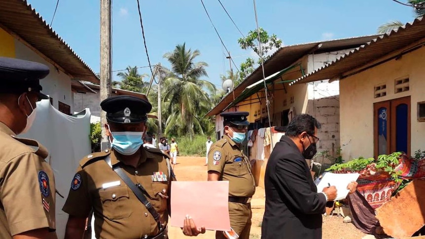 Sri Lankan magistrate Wasantha Ramanayake and police officers inspect outside a house.